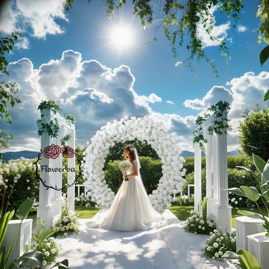 Under the blue sky and white clouds, the bride stood in front of the archway, holding her bouquet, waiting for her groom.